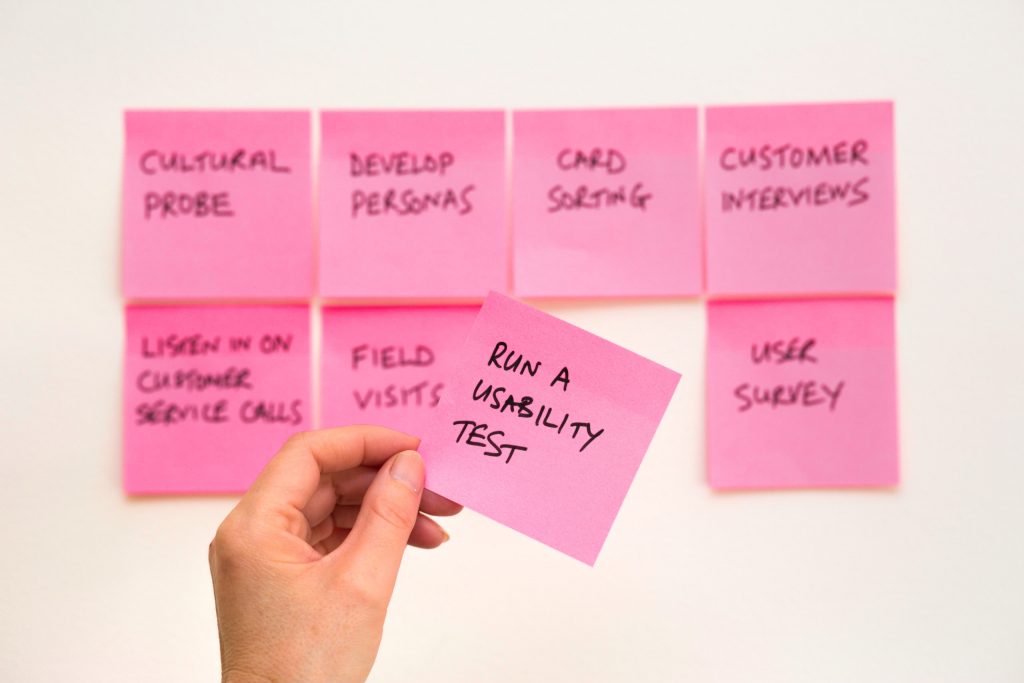 A hand takes a sticky note with "Run a usability test" written on it